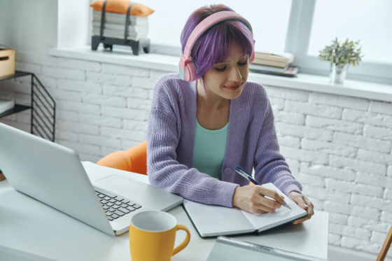 A young woman with purple hair wearing headphone is researching ways to start a business with no money