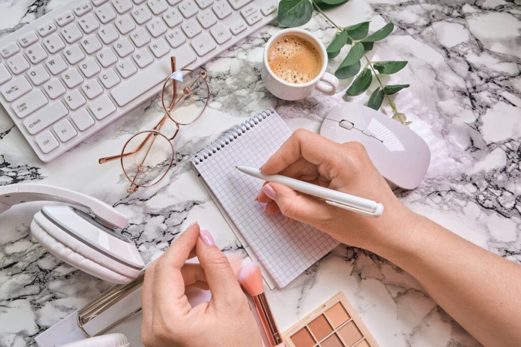 A woman working from home at a desk and writing in a notepad.