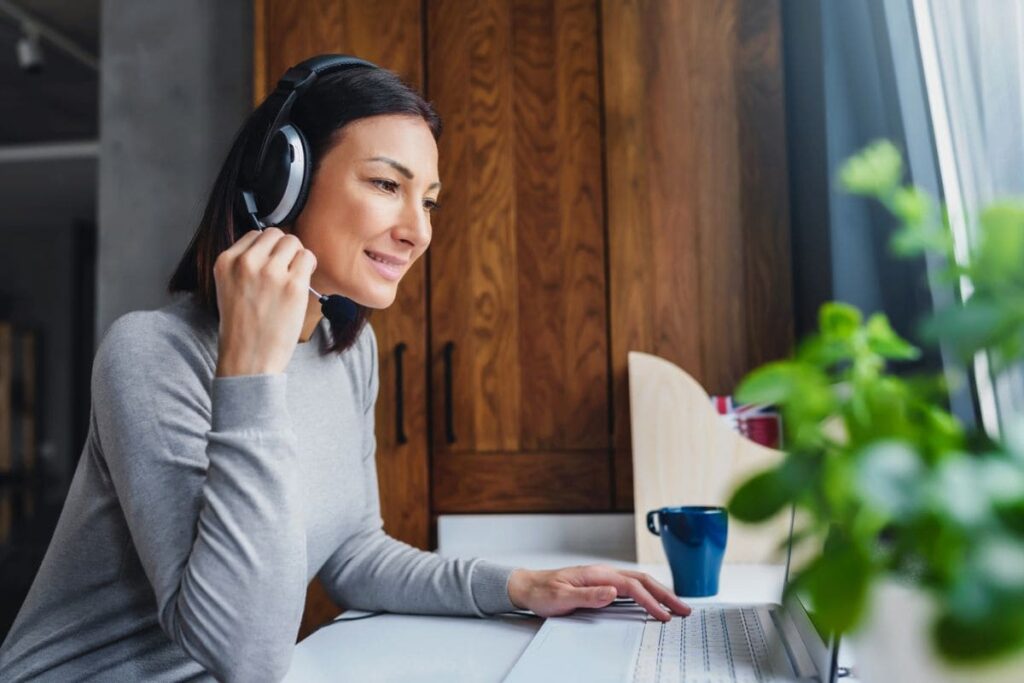 An American Express remote employee, working at her home office desk, in front of a large window.