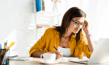 woman with brown hair and a yellow shirt working from home