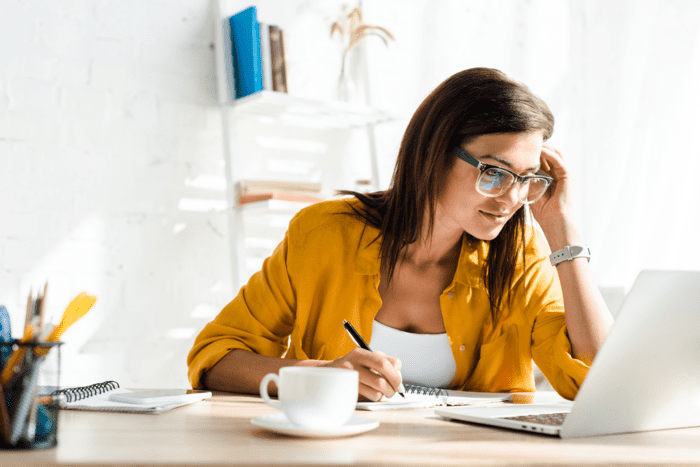 woman with brown hair and a yellow shirt working from home