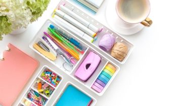 School and office supplies arranged on a homeschool mom's home office desk, with coffee and flowers.
