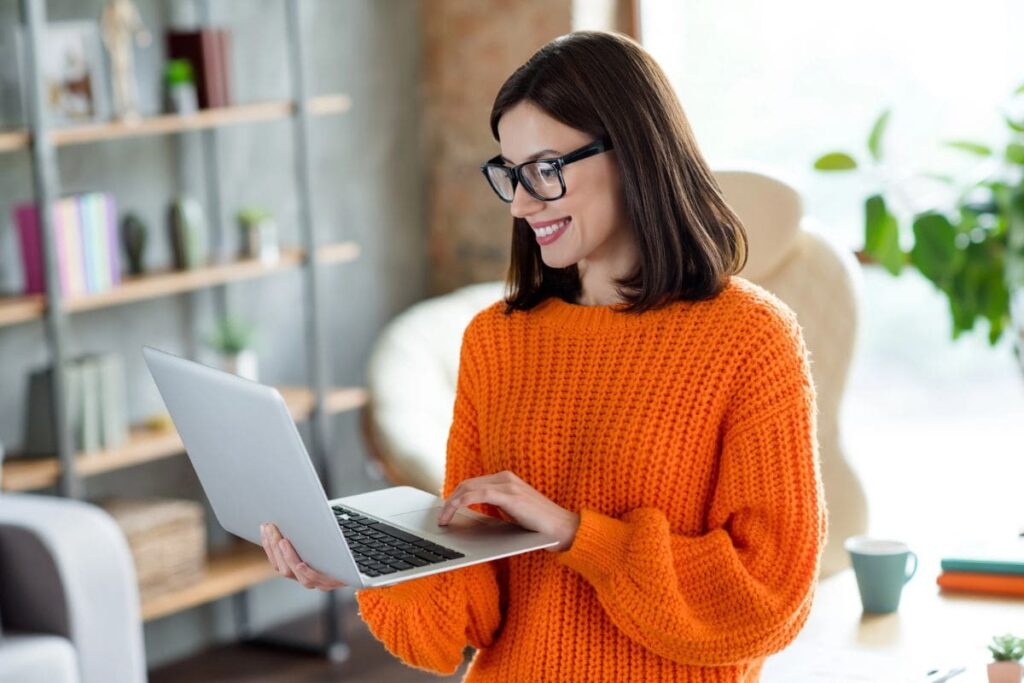 A woman using a laptop while standing in her home office.