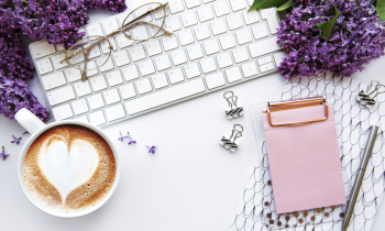 keyboard, latte, pad of paper sitting next to purple flowers