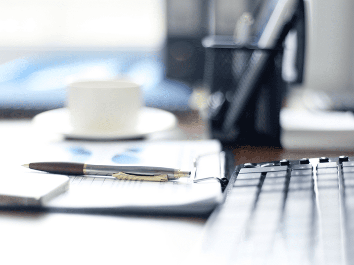 computer keyboard with notebook, pen, and coffee mug