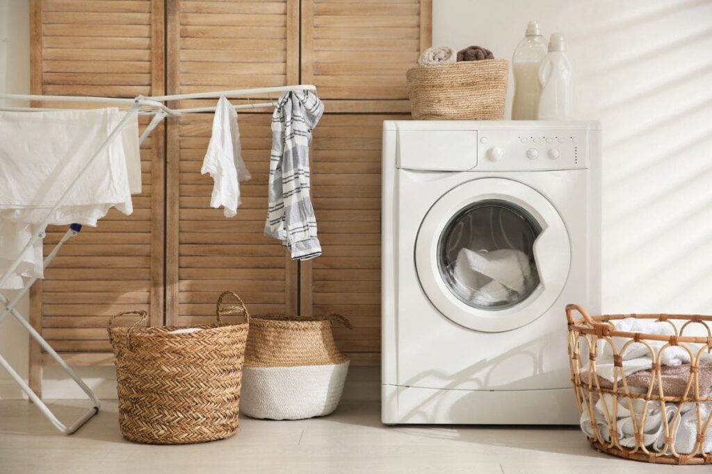 A laundry room in a remote worker's home with a washing machine, drying rack and laundry basket.