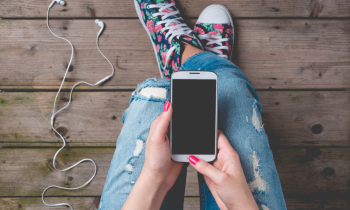 Young woman in ripped jeans and high top tennis shoes using a mobile phone