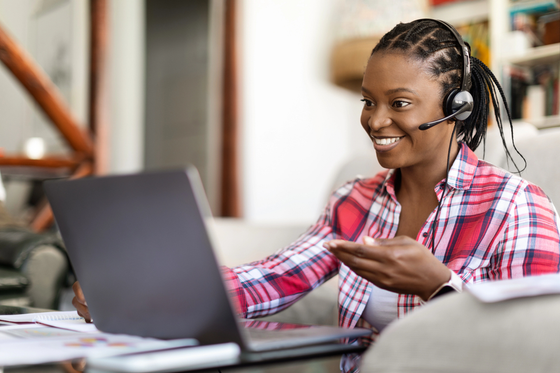 Happy positive smiling young black woman in casual outfit providing remote customer service for blog post TTEC jobs work from home