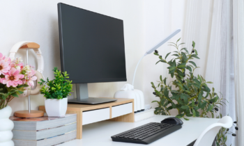 Home office space including keyboard, monitor, plants, and light for blog post home office products that promote wellness and productivity