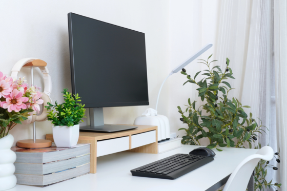 Home office space including keyboard, monitor, plants, and light for blog post home office products that promote wellness and productivity