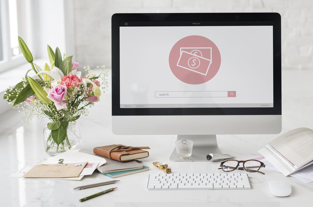 Home office space with flower, computer, books, and reading glasses