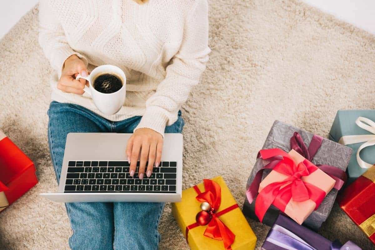 Woman working online during the holidays, among Christmas gifts.