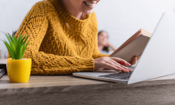 woman in a yellow sweater writing on her computer