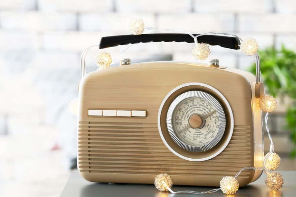 A vintage radio decorated with string lights sitting on a table.