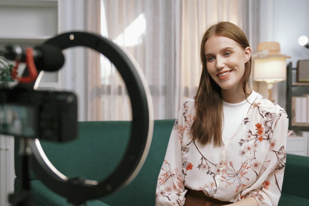 An influencer filming Walmart affiliate content from home, sitting on a couch, using a ring light.