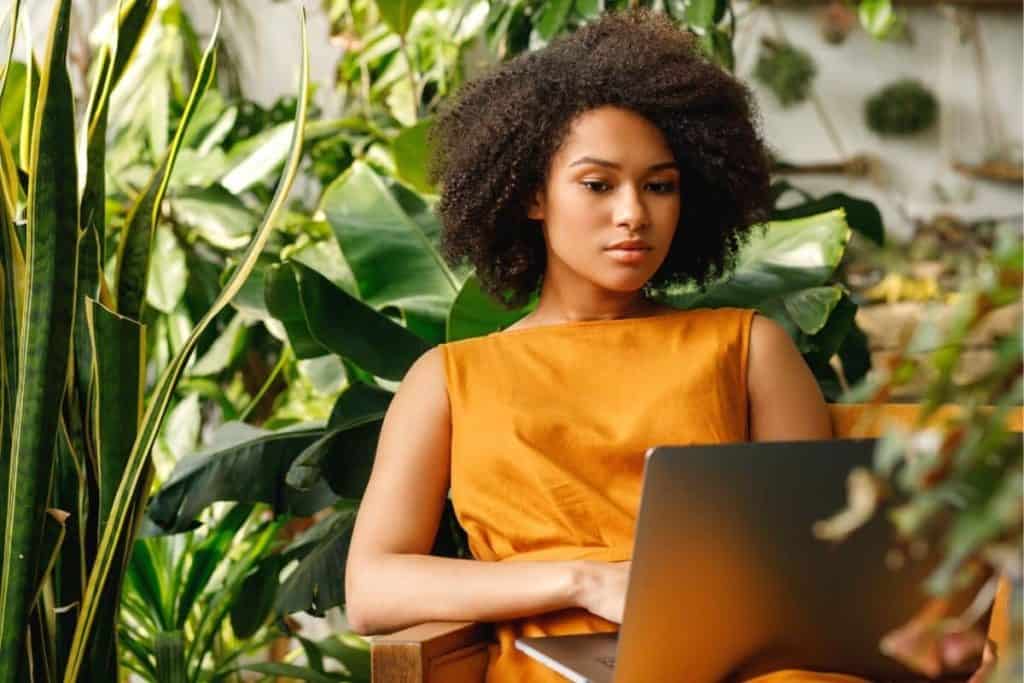 Blogger using a laptop at home office filled with plants.