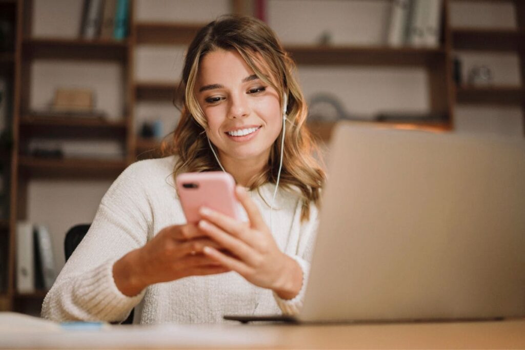 A virtual assistant working from home, using a laptop and phone.