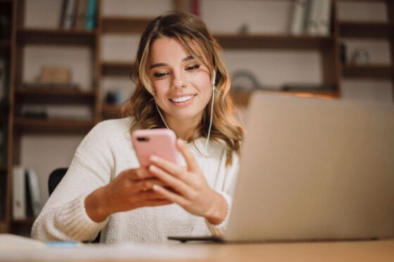 A virtual assistant working from home, using a laptop and phone for blog post create a virtual assistant portfolio
