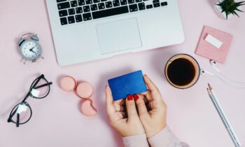 A woman holding a free Walmart giftcard while sitting at a desk.