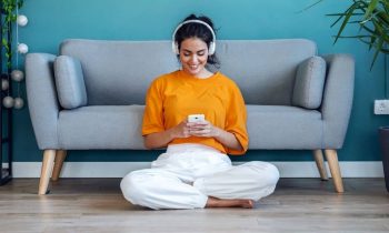 A woman sitting on the floor in her living room, wearing headphones, and getting paid to listen to music.