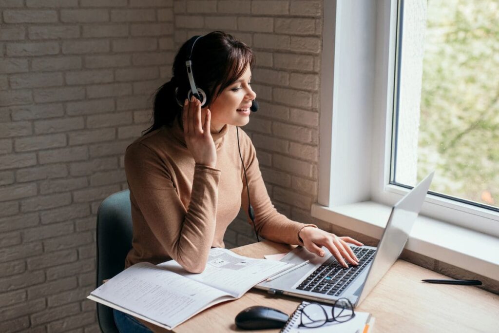 A woman working remotely from home, using a laptop to take video calls.