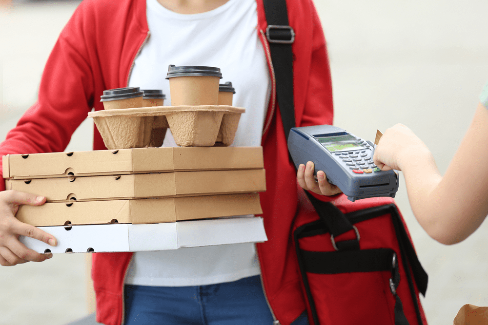 Woman delivering coffee and pizza to a customer