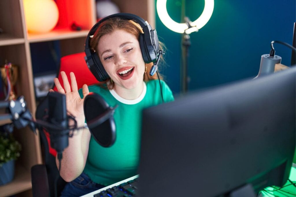 A woman streamer playing video games at a desktop computer.