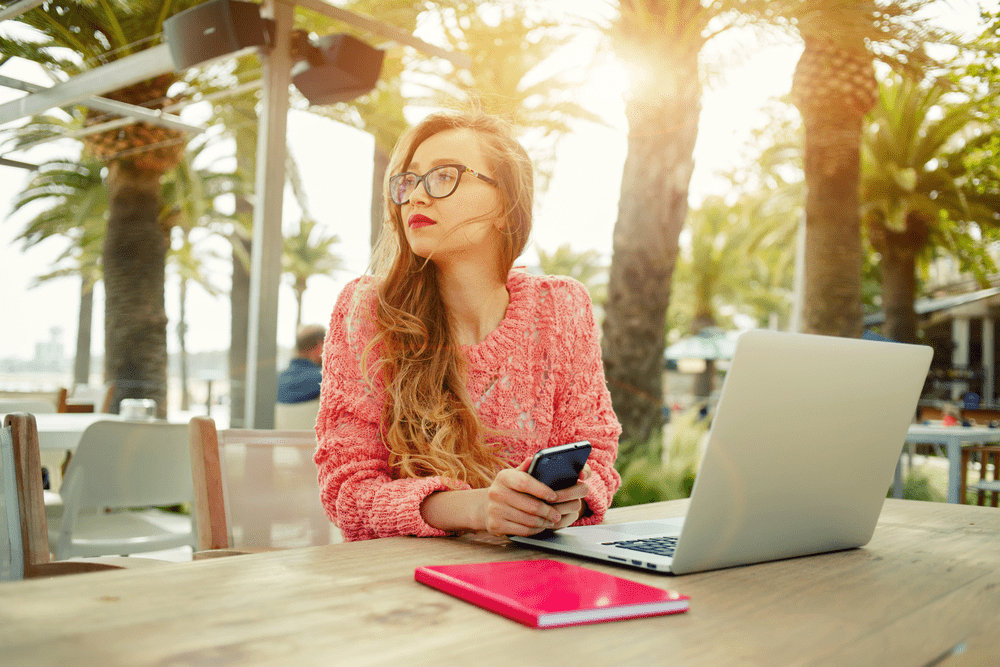 Young girl working on her laptop near the beach