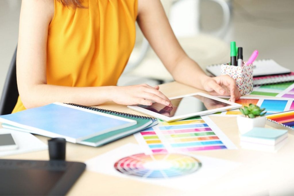 A woman working from home as a graphic designer, using a tablet to create graphics with Canva.