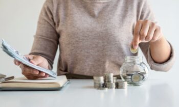 Closeup of a woman counting money at a home office desk.