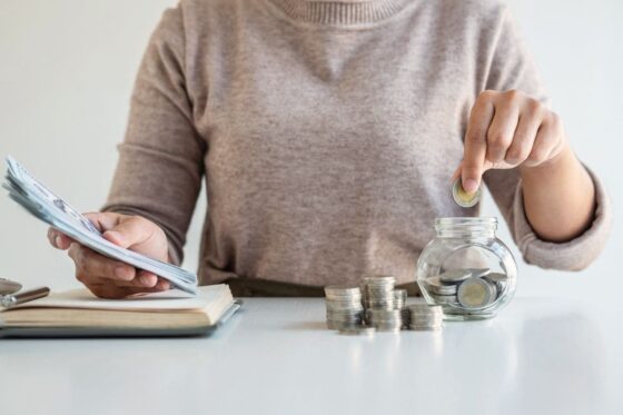 Closeup of a woman counting money at a home office desk.