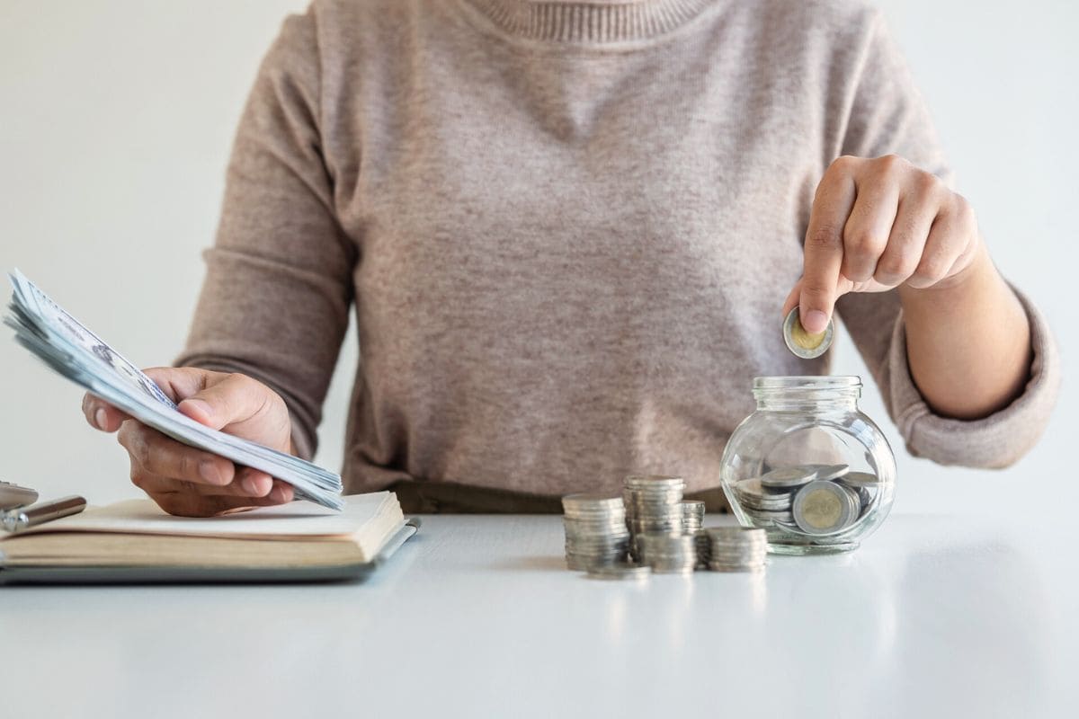 Closeup of a woman counting money at a home office desk.