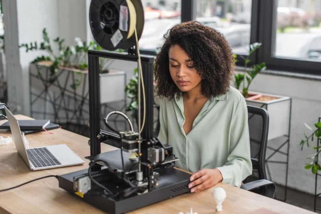 Woman working at home using a 3D printer.