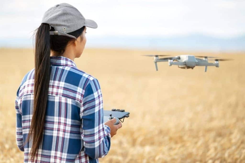 Woman standing in a grassy field and flying a drone.