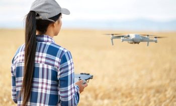 Woman standing in a grassy field and flying a drone.