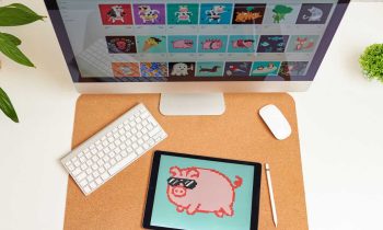 A desk with a tablet and website displaying NFT artwork.