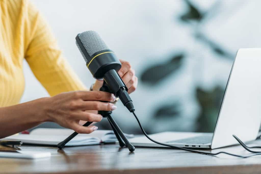 A woman working from home at a desk with a microphone and laptop.