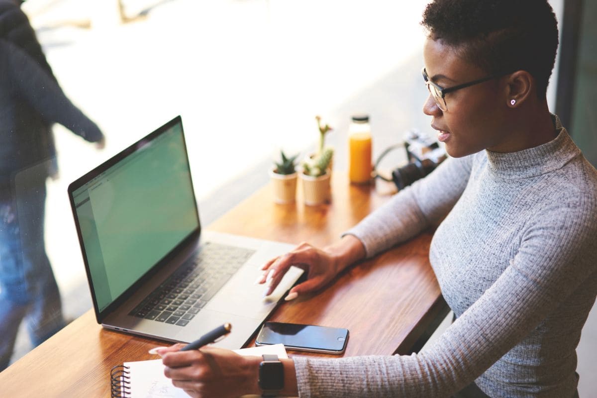 A woman working on her laptop in a cafe for the blog post market your business on Facebook