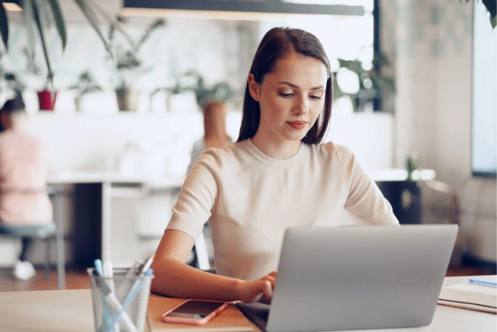 A woman sitting at a table working in a cafe on her laptop.