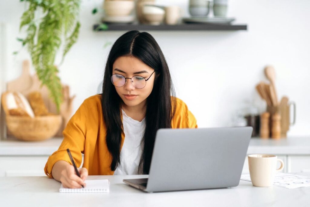 A woman working at home in her kitchen on a laptop.