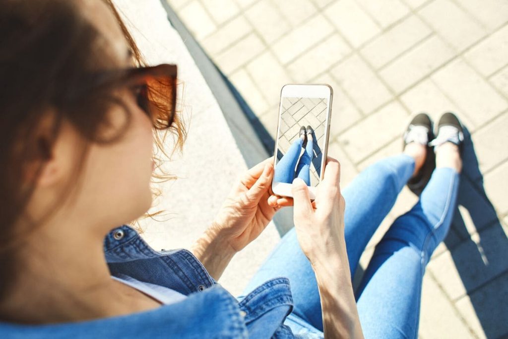 A woman using her phone to take a picture of her feet.