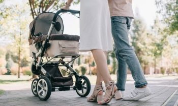 Couple walking in park with baby stroller.