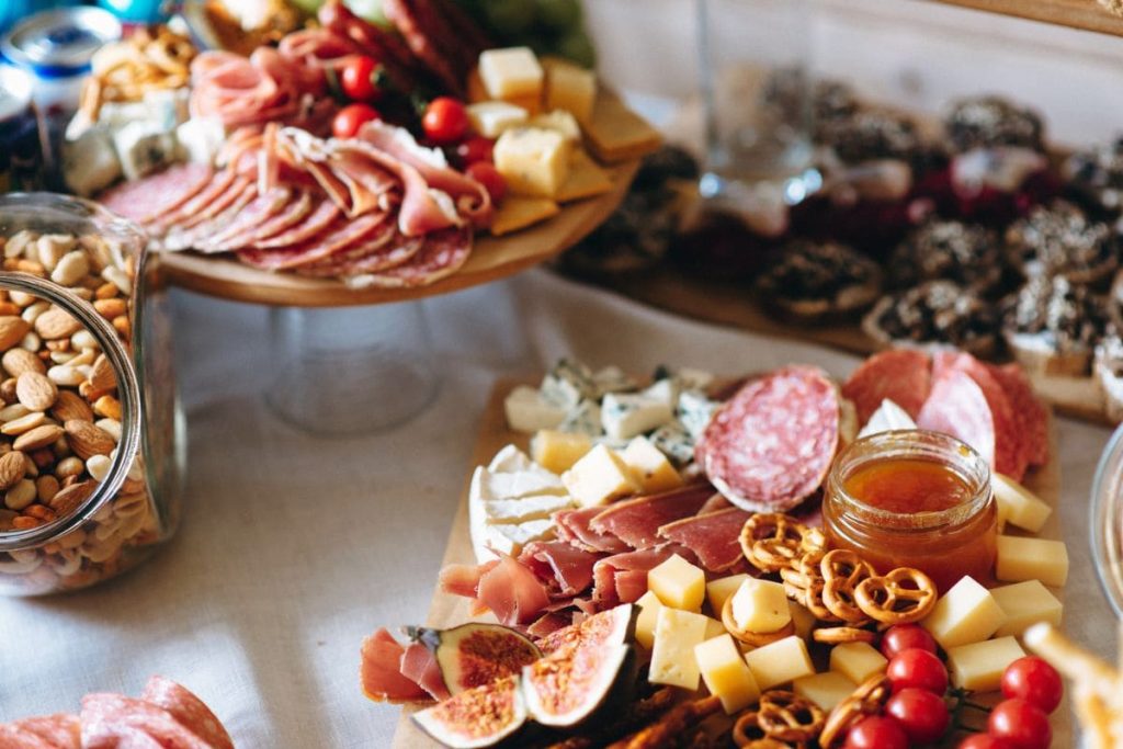Various meats, cheeses, and fruits arranged on a charcuterie board,