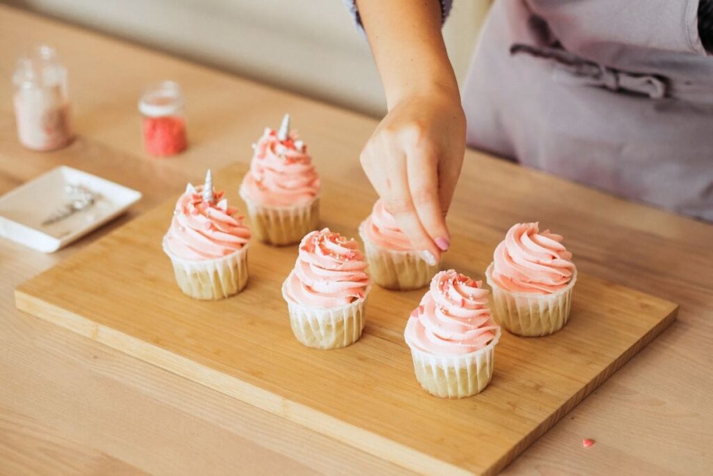 A woman decorating cupcakes in her home bakery.