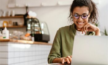 A women working remotely on a laptop in a cafe for blog post how to start a membership website.