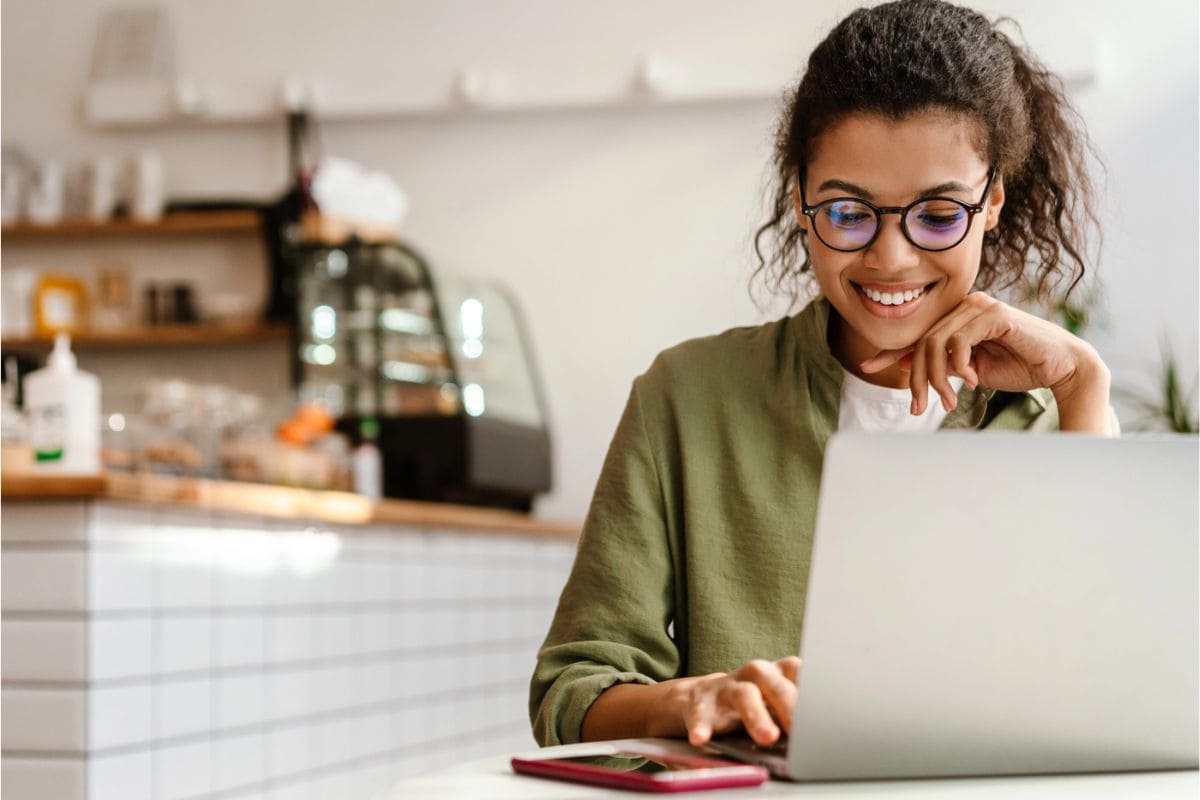 A women working remotely on a laptop in a cafe for blog post how to start a membership website.