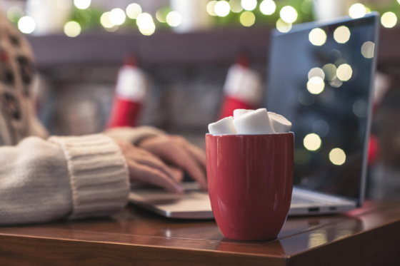 Lonely woman freelancer enjoying with cup of hot chocolate working to make Christmas cash