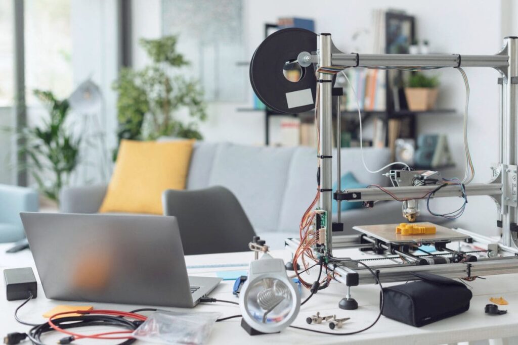 A home office desk, with a laptop, 3D printer, and other fabricating tools.