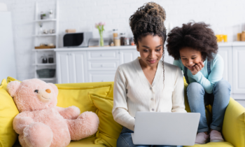 Mom and child sitting on the sofa while she looks for ways to save money for a business