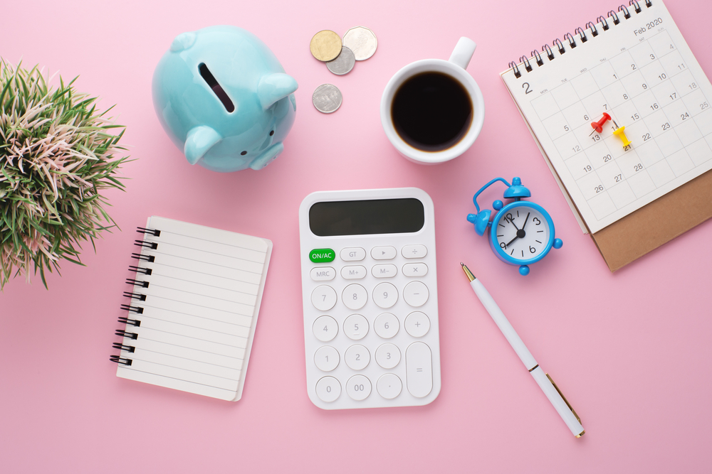 Overhead view of desk, notebook, coffee, pen, piggy bank and plant